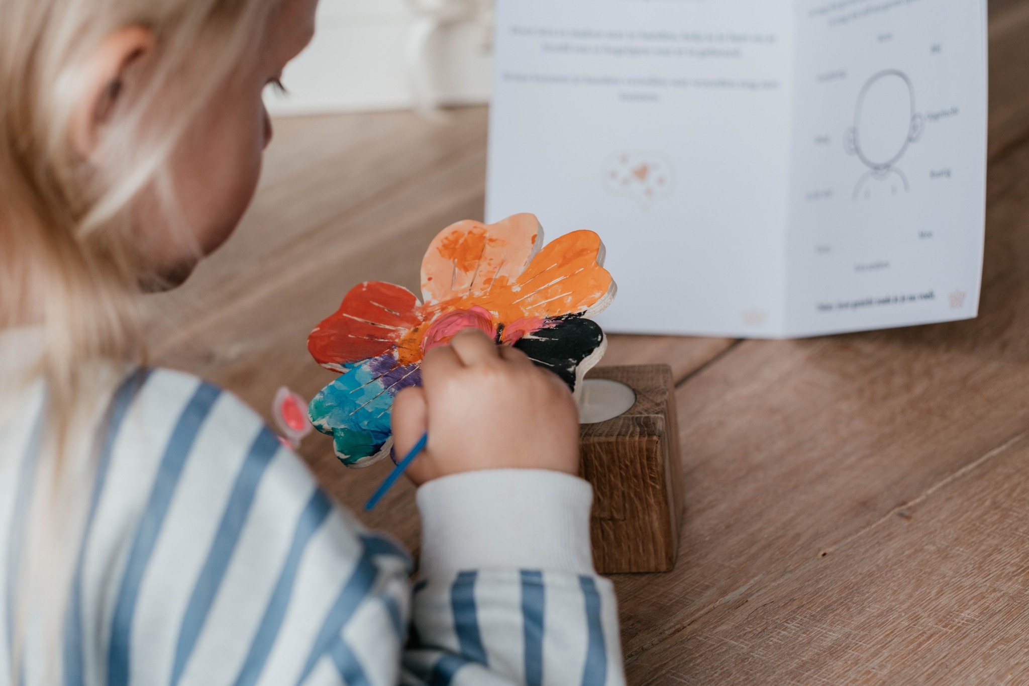 Een kind beschildert de houten bloem met verschillende kleuren